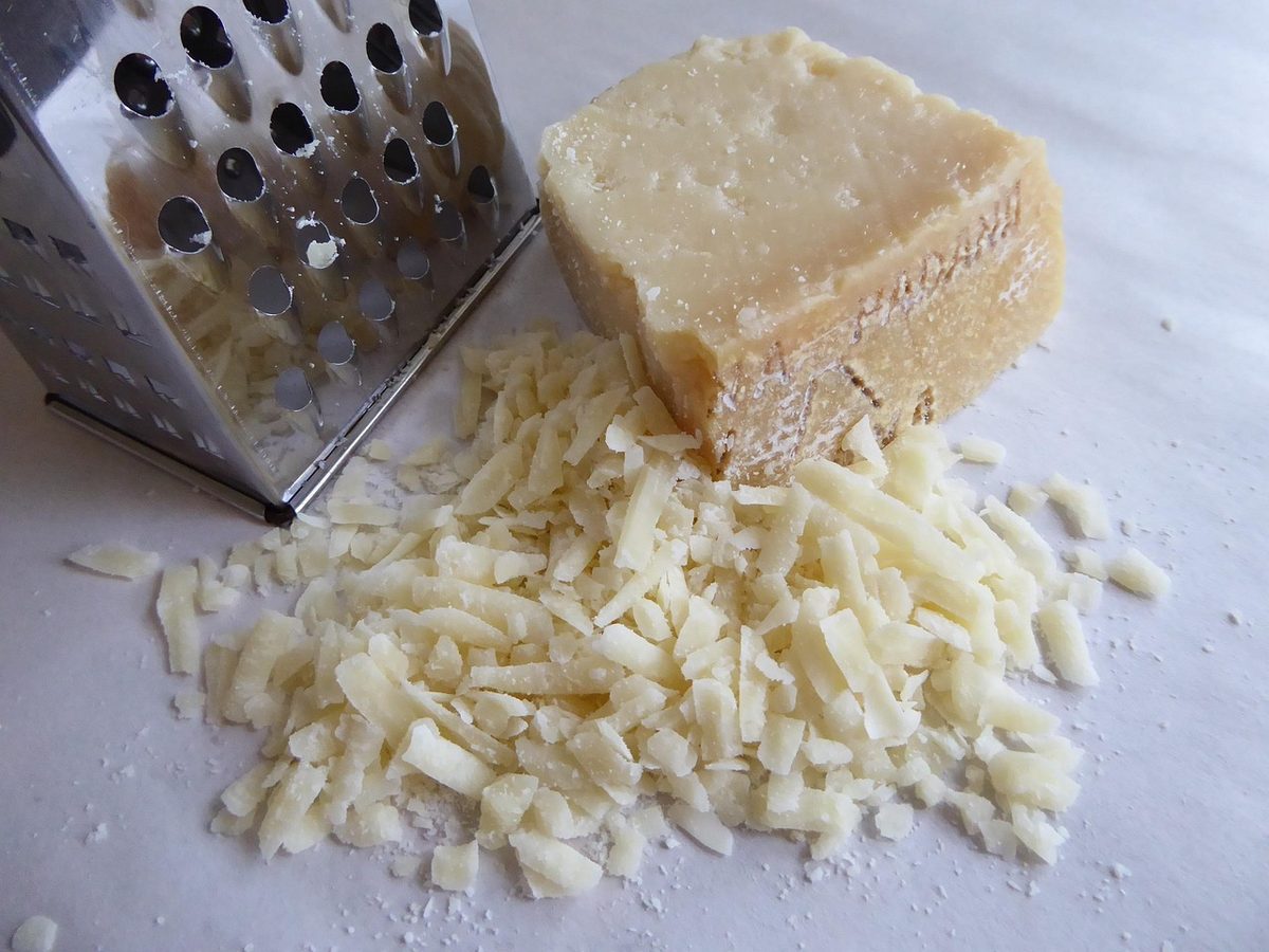 Geraspte kaas naast een keukenrasp