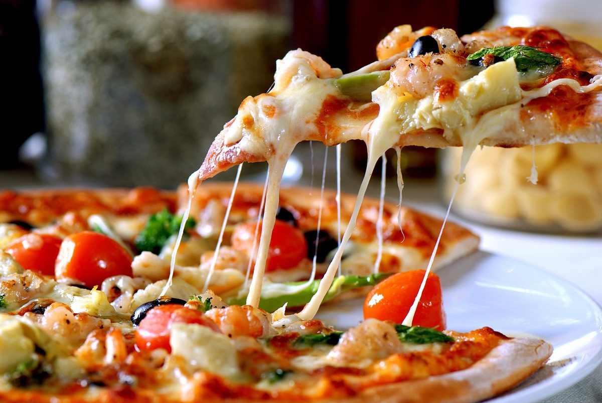 Punt pizza met gesmolten kaas van een hele pizza getild